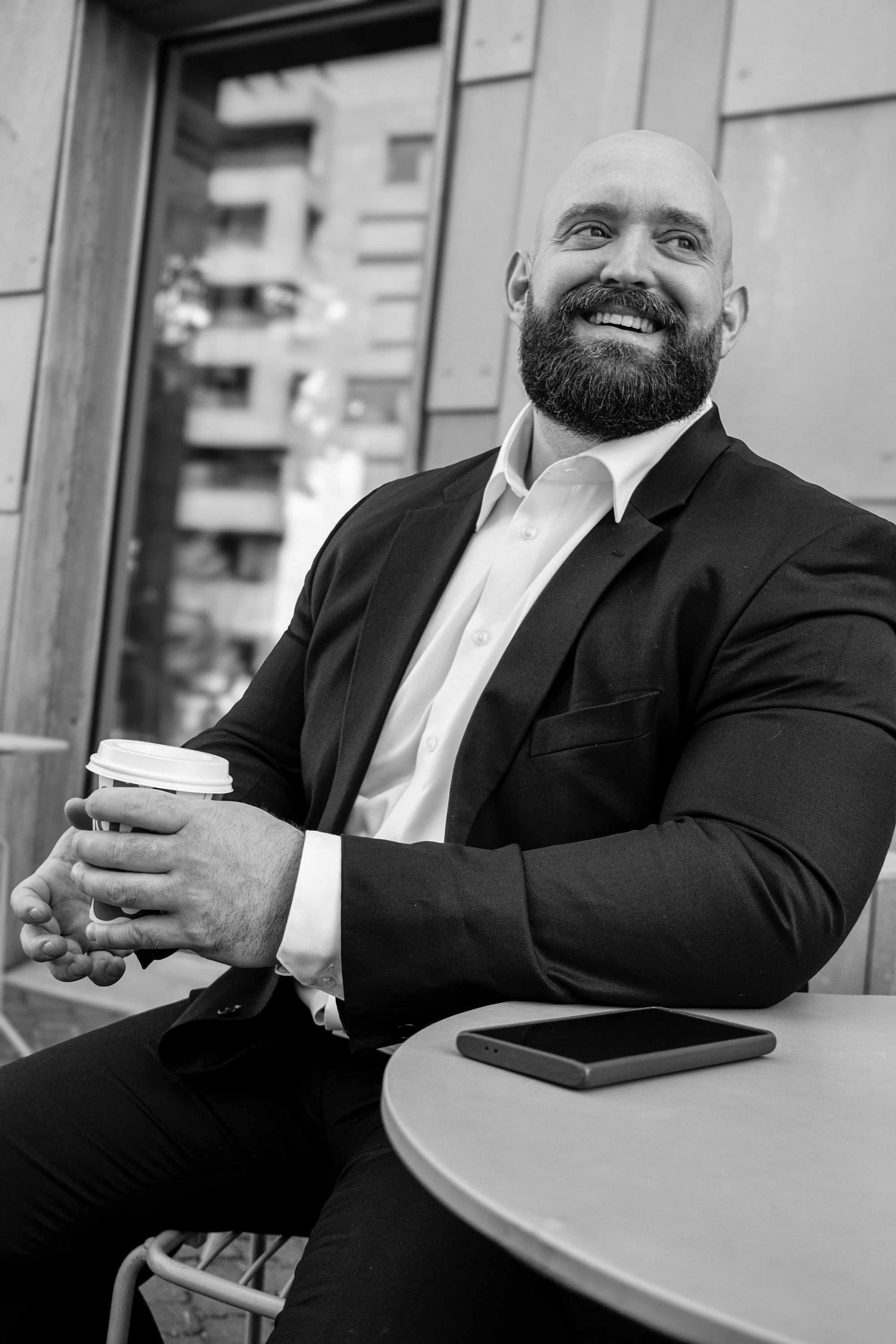 Peter R. Valderhaug smiler ved et kafébord med en kaffekopp i hendene.